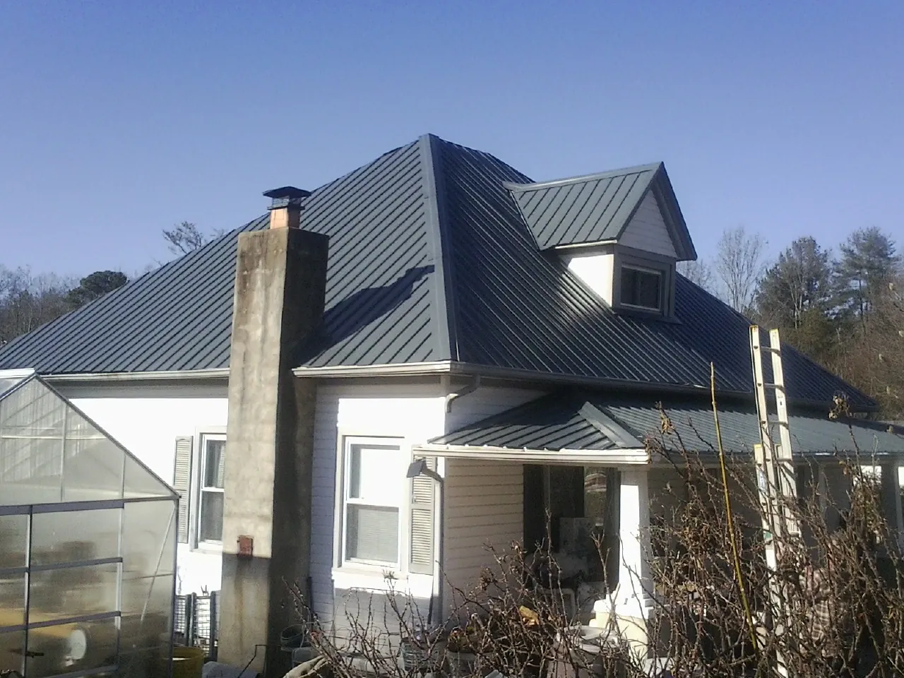 Dark blue standing seam metal roof on a white farmhouse with dormer — Slate & Tile Roof Repair by Roofing Brothers in Russell Springs