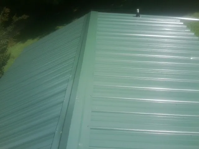 New green metal panels meeting at the ridge of a roof — Flat Roof Repair work by our crew in Russell Springs
