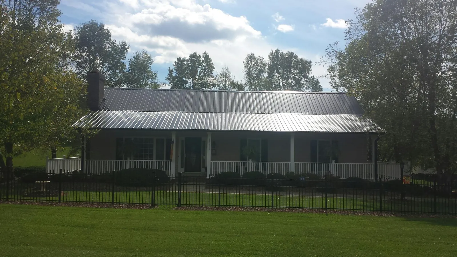 Gray metal roof on a brick ranch with a full width front porch — Gutter Guard Installation work by our crew in Russell Springs