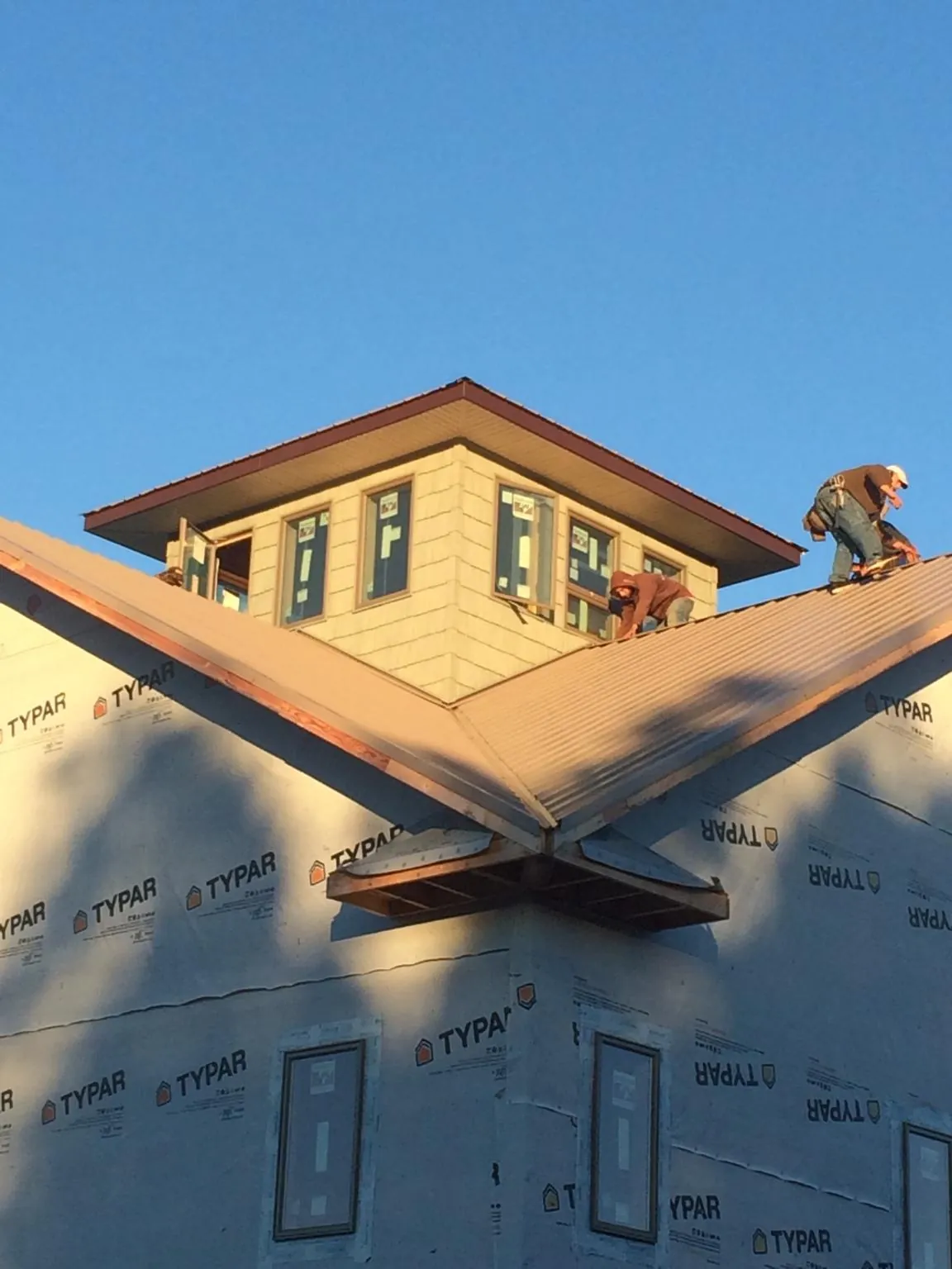 Roofers working around a rooftop cupola on a new metal roof at sunset — Roof Waterproofing in Russell Springs by Roofing Brothers